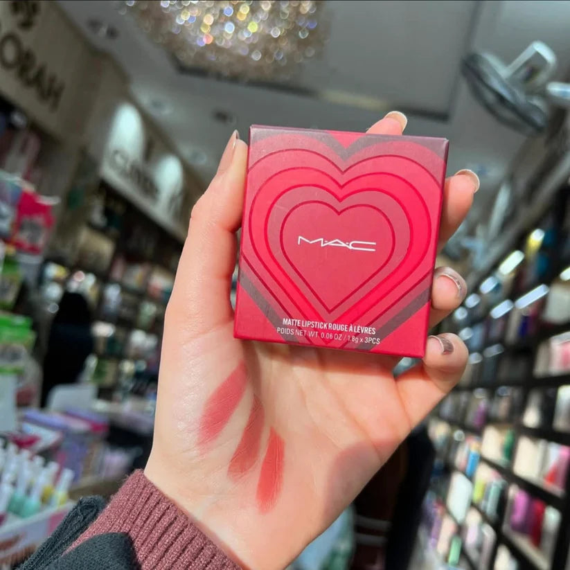 Hand holding a MAC lipstick box with heart design in a store setting