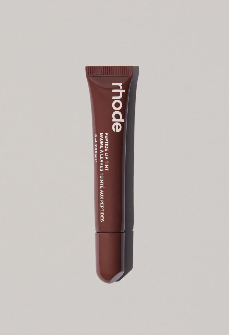 Lip tint tube with 'rhode' branding on a gray background