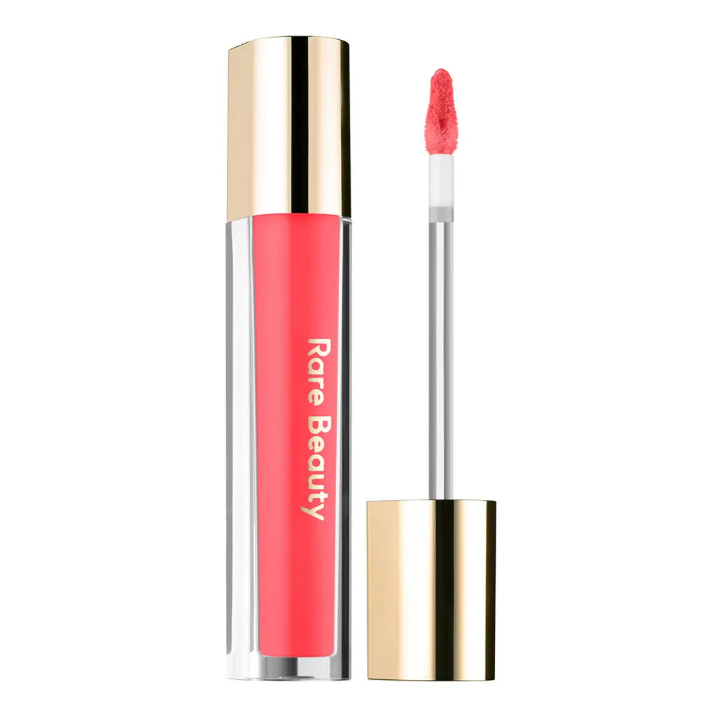 Pink lip gloss with gold cap and applicator on a white background, featuring the brand 'Rare Beauty'.